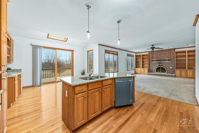 kitchen featuring dishwasher, sink, light stone counters, an island with sink, and pendant lighting