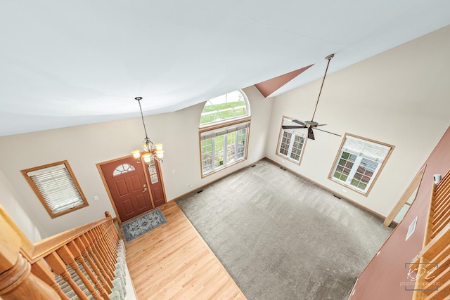 entryway featuring ceiling fan with notable chandelier, lofted ceiling, and hardwood / wood-style flooring