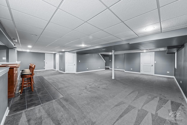 basement with dark colored carpet and a paneled ceiling