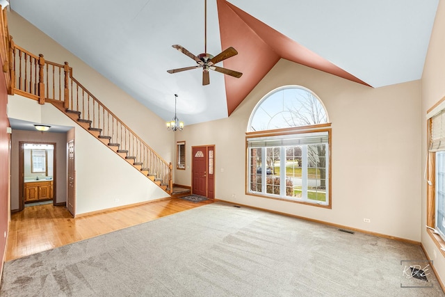 carpeted foyer entrance featuring ceiling fan with notable chandelier and high vaulted ceiling