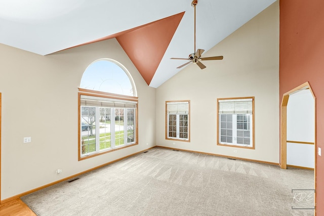 carpeted spare room featuring ceiling fan and high vaulted ceiling