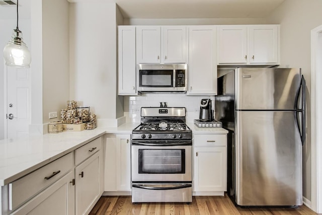 kitchen featuring stainless steel appliances, white cabinetry, and pendant lighting