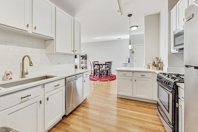 kitchen featuring appliances with stainless steel finishes, pendant lighting, white cabinetry, and sink