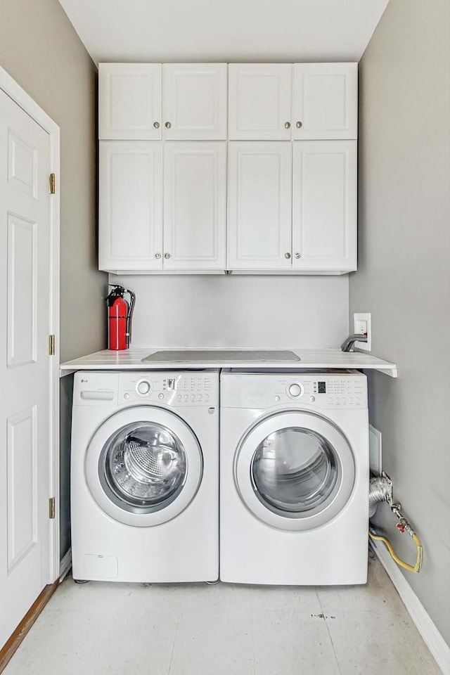 clothes washing area with washer and dryer and cabinets