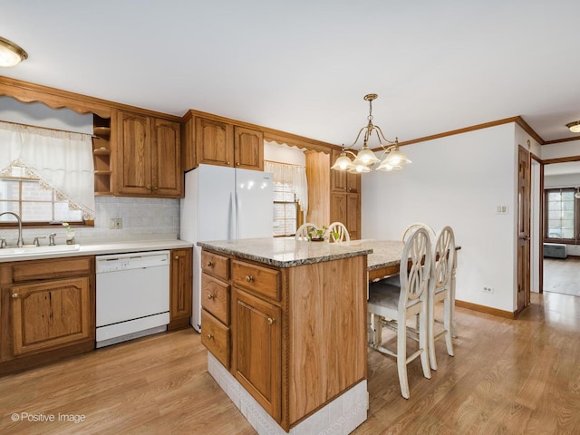 kitchen featuring pendant lighting, dishwasher, light hardwood / wood-style floors, and sink