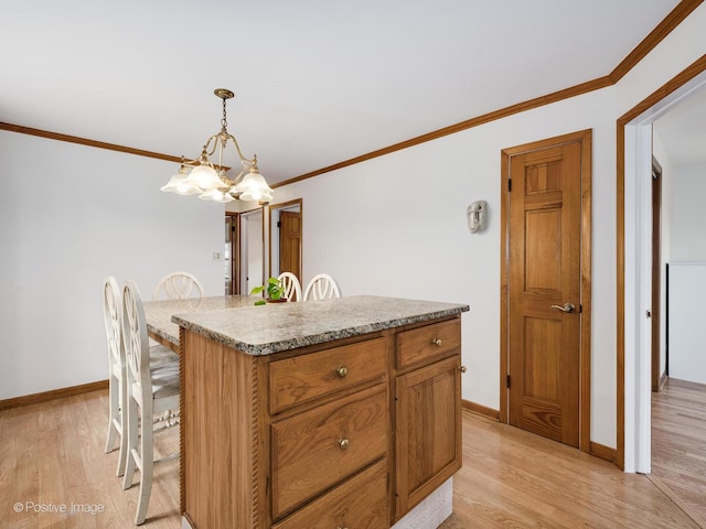 kitchen with light wood-type flooring, ornamental molding, decorative light fixtures, a chandelier, and a center island