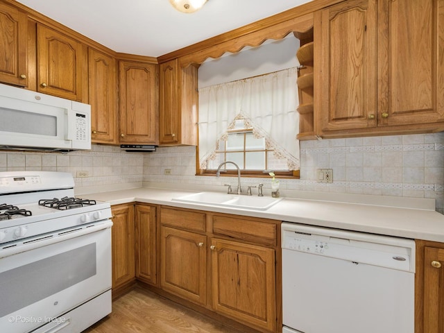 kitchen with tasteful backsplash, sink, light hardwood / wood-style floors, and white appliances