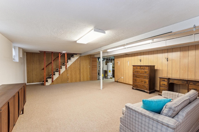 basement featuring a textured ceiling, wood walls, light colored carpet, and gas water heater