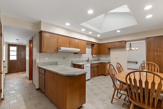 kitchen with kitchen peninsula, backsplash, white dishwasher, sink, and a chandelier