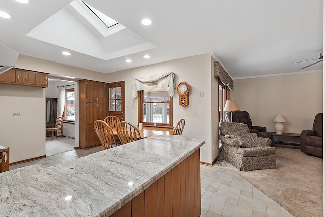 kitchen featuring light stone countertops, crown molding, ceiling fan, and a healthy amount of sunlight