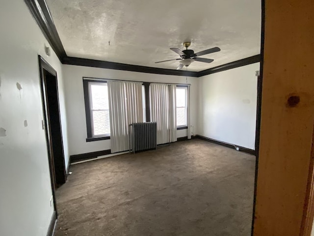 carpeted spare room featuring ceiling fan, radiator heating unit, crown molding, and a wealth of natural light