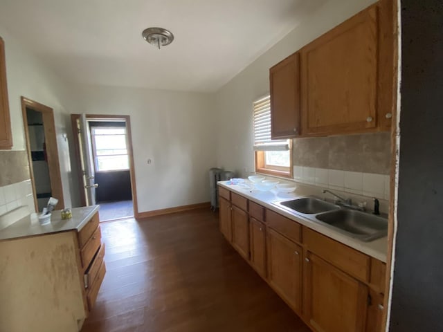 kitchen with tasteful backsplash, radiator, sink, and hardwood / wood-style flooring