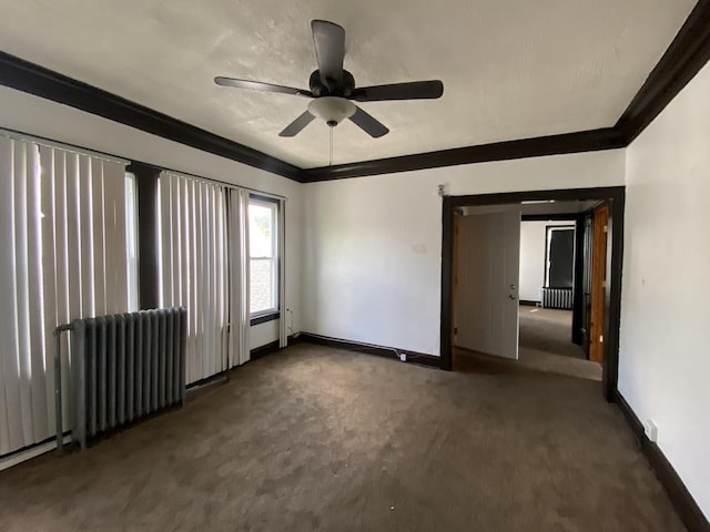 empty room with ceiling fan, radiator heating unit, dark carpet, and ornamental molding