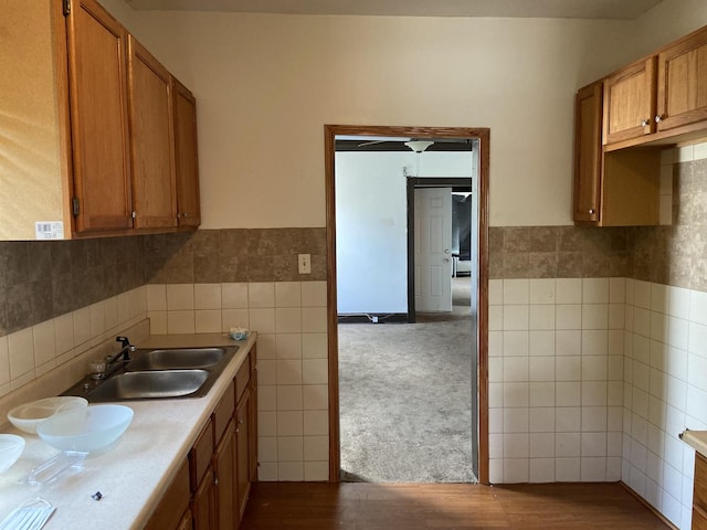 kitchen with hardwood / wood-style floors, tile walls, and sink