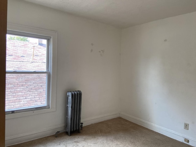 carpeted empty room with radiator heating unit