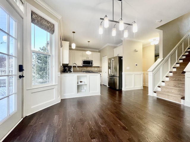 kitchen with hanging light fixtures, dark hardwood / wood-style floors, decorative backsplash, white cabinetry, and stainless steel appliances