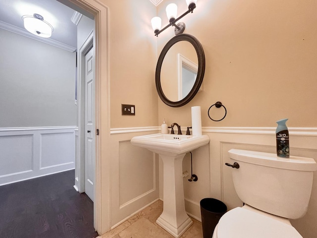 bathroom with wood-type flooring, toilet, and crown molding