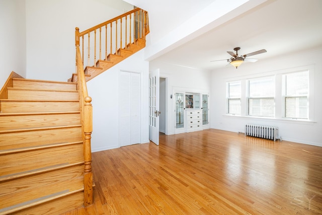 unfurnished living room with hardwood / wood-style flooring, radiator heating unit, and ceiling fan