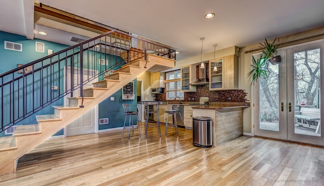 kitchen with a healthy amount of sunlight, french doors, kitchen peninsula, and light hardwood / wood-style flooring