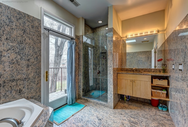 bathroom with vanity, shower with separate bathtub, and tile walls