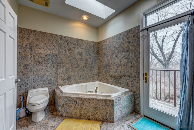 bathroom featuring a relaxing tiled tub, toilet, tile walls, and a skylight