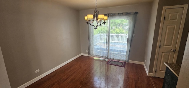 unfurnished dining area featuring a chandelier and dark wood-type flooring