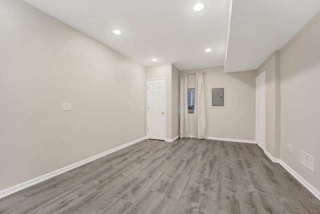 empty room featuring electric panel and light hardwood / wood-style flooring