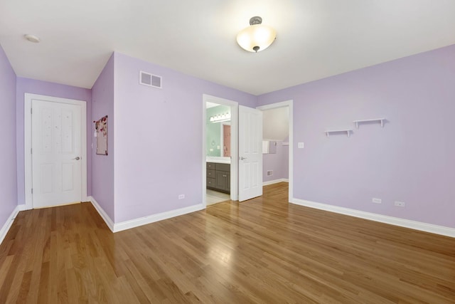 unfurnished bedroom with ensuite bath, a closet, and light wood-type flooring