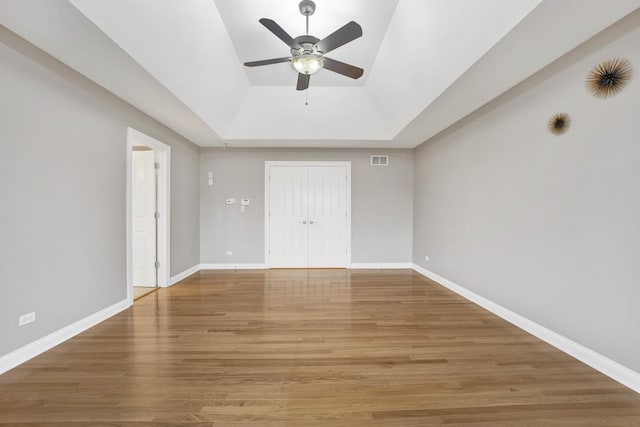 interior space featuring wood-type flooring, a closet, a raised ceiling, and ceiling fan