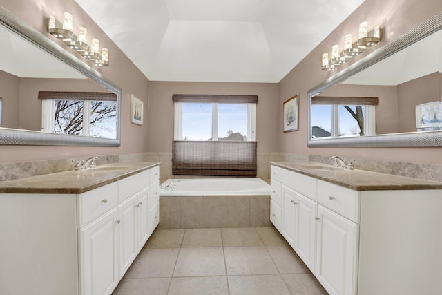 bathroom featuring tiled bath, vanity, a tray ceiling, and tile patterned floors