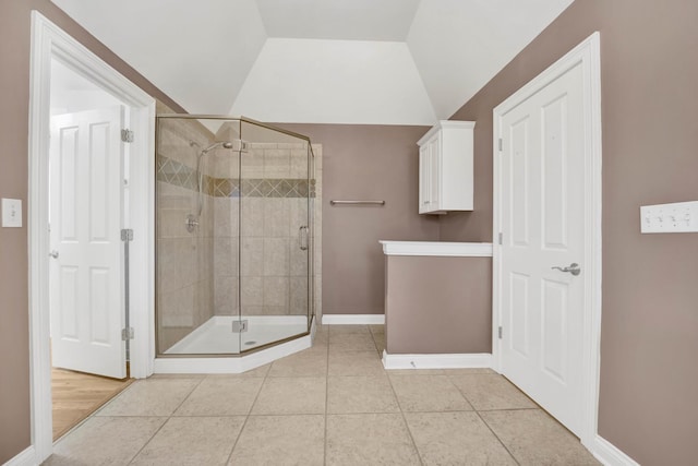 bathroom featuring tile patterned floors, a shower with shower door, and vaulted ceiling