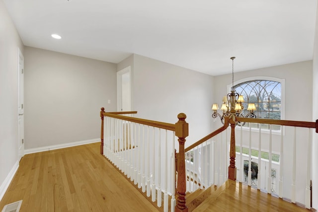 corridor with a chandelier, light hardwood / wood-style flooring, and a wealth of natural light