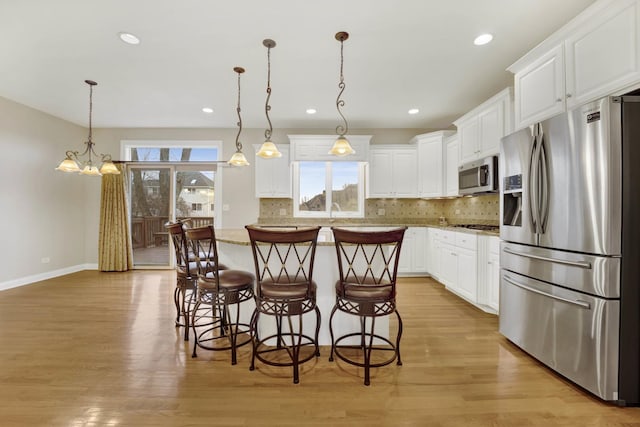 kitchen with white cabinetry, a kitchen island, hanging light fixtures, and appliances with stainless steel finishes