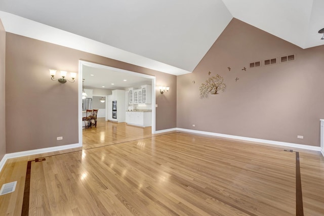 unfurnished living room with wood-type flooring and high vaulted ceiling