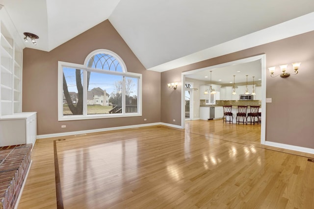 unfurnished living room featuring light wood-type flooring and vaulted ceiling