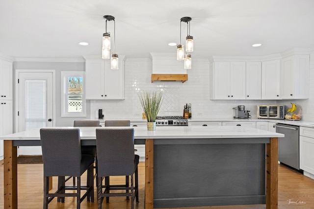 kitchen featuring dishwasher, a center island, decorative light fixtures, white cabinetry, and a breakfast bar area