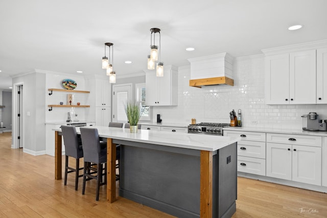 kitchen featuring white cabinets, light stone counters, stainless steel stove, and a kitchen island