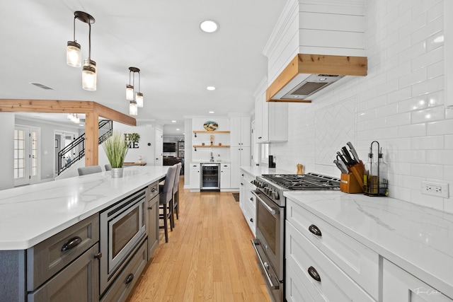 kitchen featuring stainless steel appliances, white cabinetry, tasteful backsplash, beverage cooler, and pendant lighting