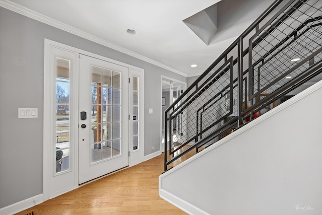 entrance foyer with ornamental molding and light hardwood / wood-style floors