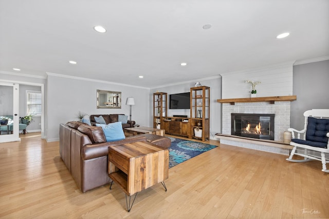 living room with light hardwood / wood-style floors, crown molding, and a fireplace