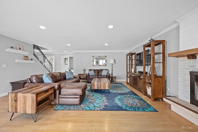 living room with a fireplace, ornamental molding, and light hardwood / wood-style floors