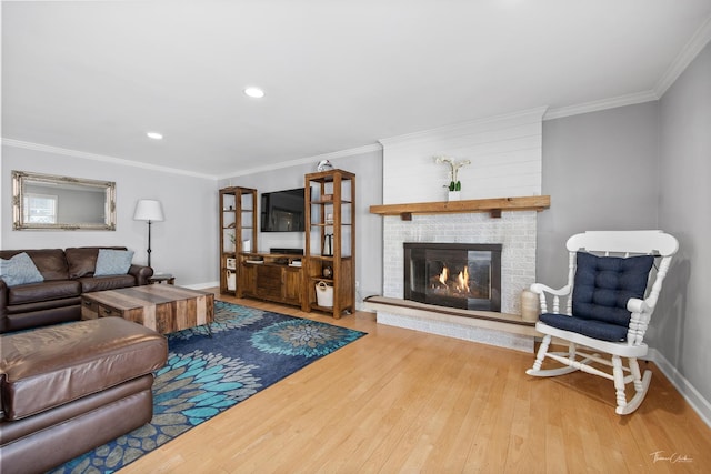 living room with a brick fireplace, crown molding, and hardwood / wood-style floors