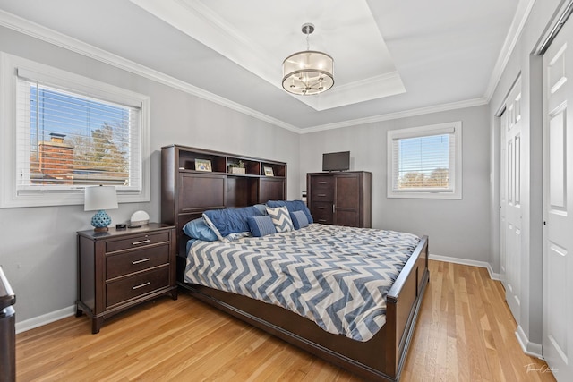 bedroom with ornamental molding, light hardwood / wood-style flooring, a raised ceiling, and a notable chandelier