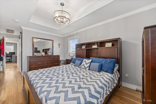 bedroom with a raised ceiling, a notable chandelier, light hardwood / wood-style floors, and crown molding