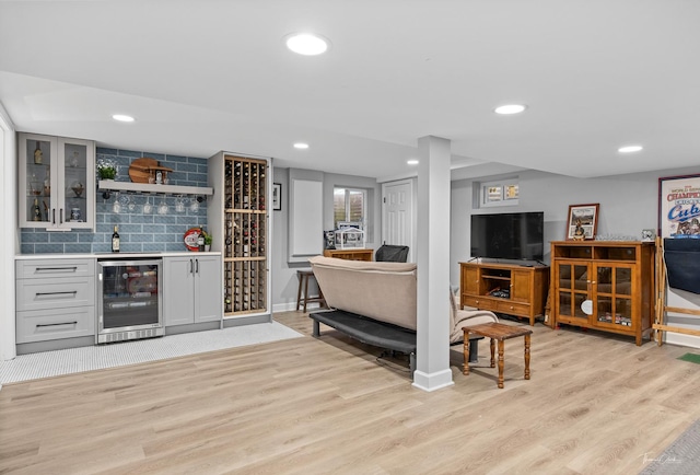 bar with light hardwood / wood-style flooring, beverage cooler, gray cabinets, and tasteful backsplash