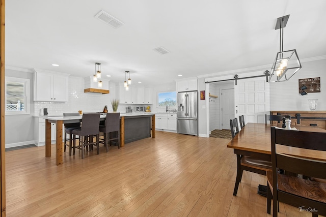 dining room featuring ornamental molding, a barn door, and light hardwood / wood-style flooring