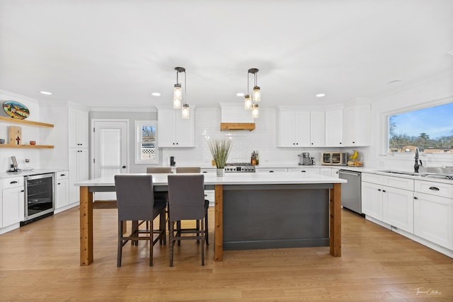 kitchen with beverage cooler, hanging light fixtures, a kitchen bar, a kitchen island, and sink