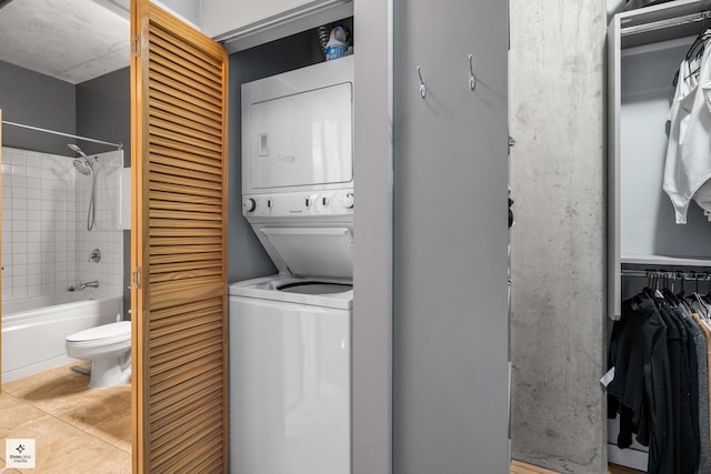 clothes washing area featuring stacked washer / drying machine and light tile patterned floors