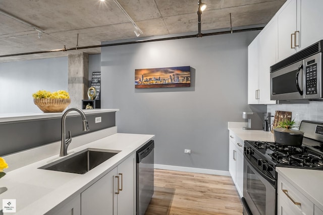 kitchen with sink, white cabinets, stainless steel appliances, and light hardwood / wood-style floors