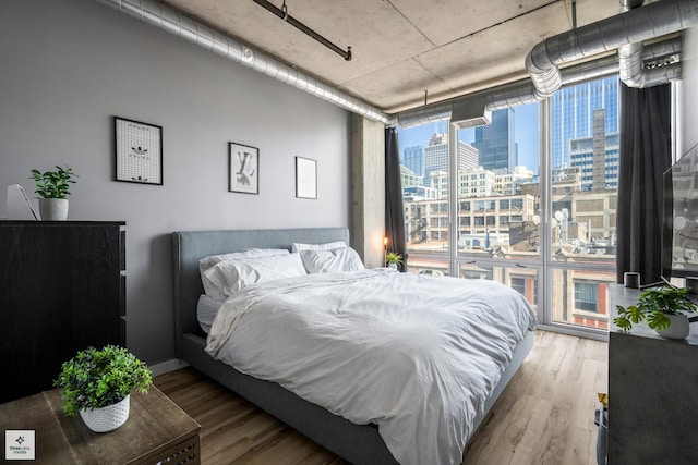 bedroom with hardwood / wood-style floors and expansive windows